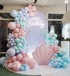 there is a birthday sign made out of balloons and mermaid tailes on the table