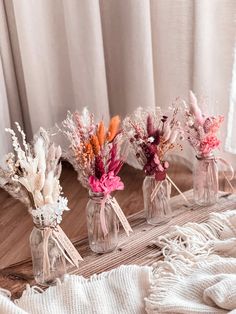 three vases filled with flowers on top of a wooden table