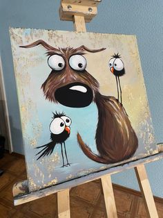 an easel with a painting of a dog and two birds on it's face