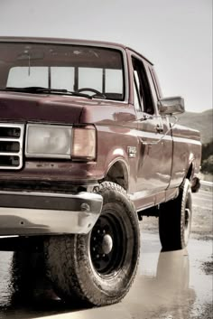 a red pick up truck parked in the mud