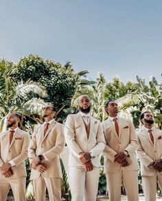 a group of men standing next to each other wearing suits and ties with palm trees in the background