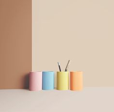 three different colored pencils sitting on top of each other in front of a wall