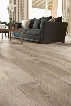 a living room filled with furniture and a wooden floor covered in hard wood planks