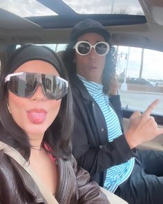 two people sitting in the back seat of a car, one with sunglasses on her head