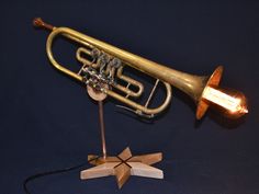 an old brass trumpet is sitting on a stand with a wooden star next to it