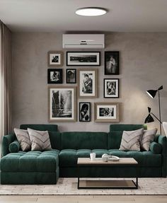 a living room with green couches and pictures on the wall above them, along with a coffee table