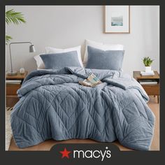 an image of a bed with blue comforter and pillows on it in a bedroom