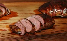 sliced meat sitting on top of a wooden cutting board next to another piece of meat