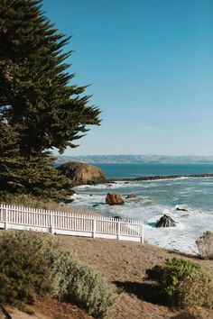 a white picket fence next to the ocean