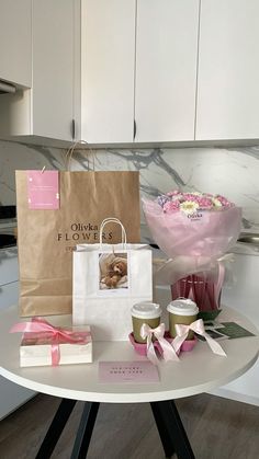 a table topped with bags and flowers on top of a white tablecloth covered in pink ribbon