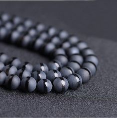 a close up of a beaded necklace on a black surface with white and gray beads