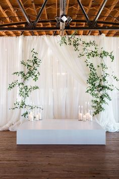 a white stage set up with candles and greenery