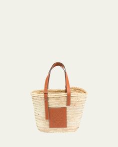 Loewe woven palm leaf basket bag. Calf leather tote handles. Front patch with embossed logo. Approx. 7"H x 13"W x 5"D. Made in Spain. Designer Rectangular Straw Bag With Braided Handles, Designer Straw Tote Bag With Bamboo Handle, Designer Natural Basket Straw Bag, Designer Natural Color Basket Straw Bag, Designer Straw Basket Bag With Leather Handles, Designer Straw Basket Bag With Braided Handles, Designer Woven Leather Basket Bag, Designer Basket Bag In Woven Leather, Luxury Rectangular Straw Bag With Rolled Handles