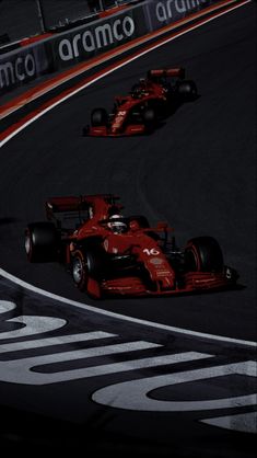 two racing cars on a race track with the lights on and one driving behind them