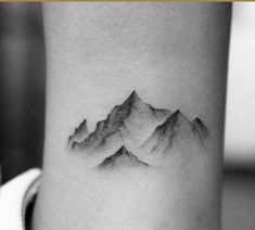 a small mountain tattoo on the right side of the arm is shown in black and white