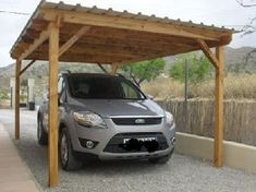 a car is parked under a wooden carport