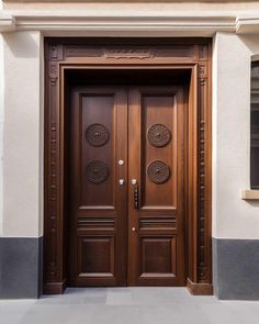 two wooden doors are shown in front of a building