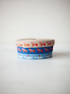 three rolls of washi tape with horses on blue and red designs, sitting on a white surface