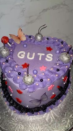 a heart shaped cake with the word guts written on it and decorations around the edges