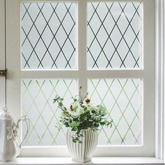 a vase with flowers sitting on a window sill next to a teapot and pitcher