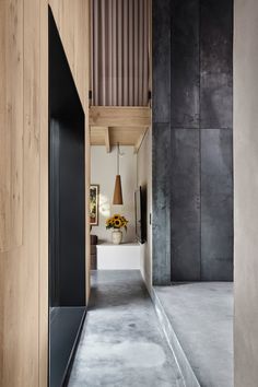 the hallway is very narrow and has wooden paneling on the walls, along with concrete flooring