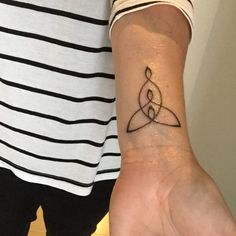 a woman's wrist with a tattoo on it that has an intertwined symbol