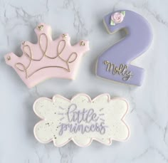 three decorated cookies with the number 2, two little princesses and one big crown