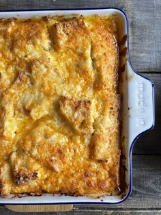 a casserole dish with meat and cheese in it sitting on a wooden table