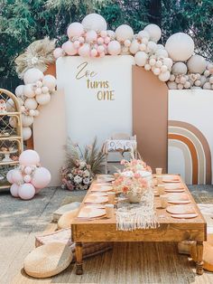 a table set up for a party with pink and white balloons on the back wall