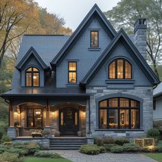 a large gray house with lots of windows and lights on the front door is lit up at night