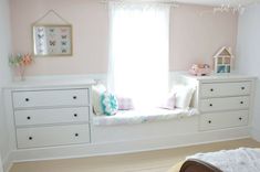 there is a window seat in the corner of this child's room with white furniture