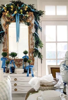 a white dresser topped with a mirror next to a table covered in plates and bowls