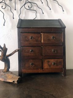 an old wooden dresser sitting on top of a table next to a small figurine