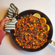 a skillet filled with cooked vegetables on top of a white table next to a striped napkin