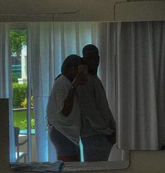 a man and woman standing in front of a mirror