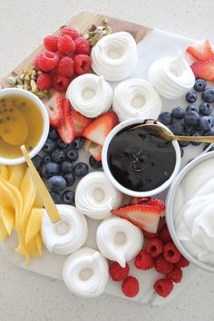 fruit and yogurt dips are arranged on a cutting board with spoons