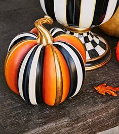 two striped pumpkins sitting on top of a wooden table next to other decorative items