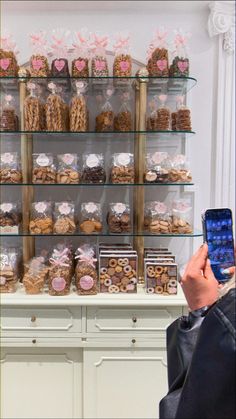 a person holding up a cell phone in front of a display case filled with cookies