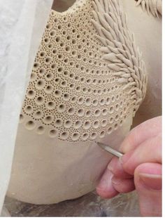 a person working on a clay sculpture with a crochet stitching pattern around it