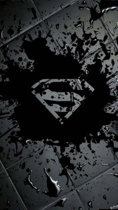 a black and white photo of a superman symbol on the ground with water droplets around it