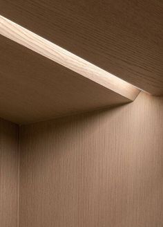 the corner of a wood paneled room with light coming from it's ceiling