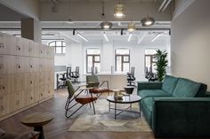 an office with green couches and chairs in the middle of it, surrounded by lockers