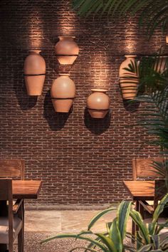 several vases are hanging on the brick wall