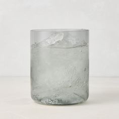 a glass filled with ice and water on top of a white countertop next to a wall