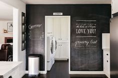 a laundry room with chalkboard walls and white cabinets, along with a washer and dryer