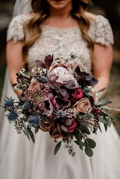 a bride holding a bouquet of flowers in her hands and looking down at the camera