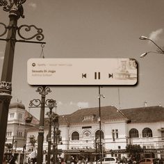 a street sign in front of a large building with many windows and people walking around