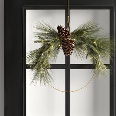 a pine cone wreath hanging on a window sill