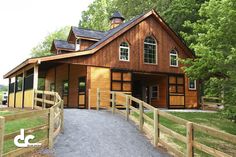 a large wooden house with a fence around it's perimeter and trees in the background