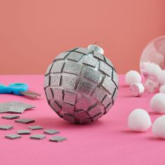 a pink table topped with lots of white balls next to scissors and other items on top of it